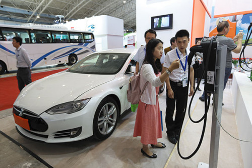 Visitors at a recent new-energy vehicle expo in Beijing examine charging posts. The city is suffering from a shortage of the facilities. （Photo/China Daily）