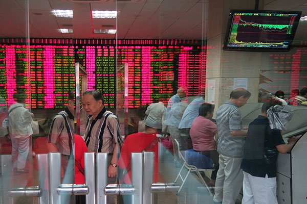 Investors monitor share prices at a securities brokerage in Shanghai on Monday. The Shanghai Composite Index opened 7.8 percent higher, but ended the day up only 2.4 percent, at 3,775.91 points, in response to unprecedented rescue measures announced over the weekend. (Photo/China Daily)