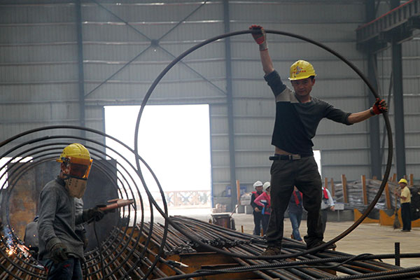 Workers at a bridge construction site in Pingtan, Fujian province. The government has accelerated the approval of infrastructure projects in the hope of boosting sluggish fixed-asset investment. (Photo/China Daily)