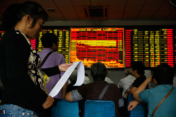 An investor checks her trading records at a brokerage in Shanghai on Tuesday. The benchmark Shanghai Composite Index has fallen by about 30 percent in the past three weeks. (Photo/China Daily)