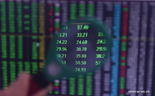 An investor looks through stock information with a magnifier in Shenyang, capital of northeast China's Liaoning Province, July 8, 2015. (Photo: Xinhua/Yang Qing)