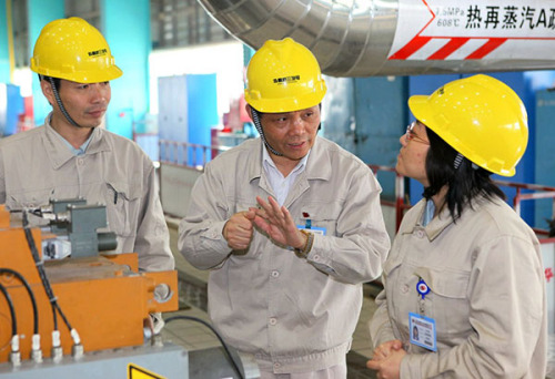 Feng Weizhong (middle) talks to colleagues during an on-site inspection at the Shanghai Waigaoqiao No 3 Power Generation Co Ltd. (Photo/Provided to China Daily)