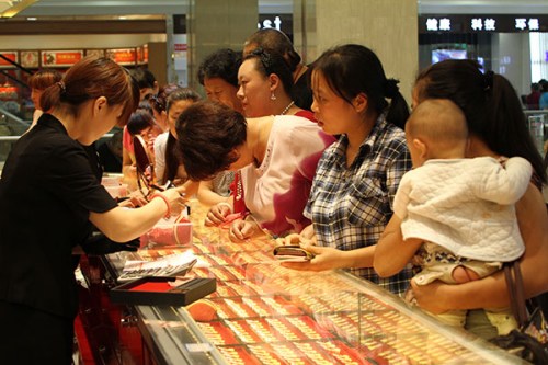 Customers buy gold jewelry at a shopping center in Xuchang, Henan province. China's central bank said that its bullion reserves have increased 57 percent to 1,658 metric tons since 2009. Photo/China Daily
