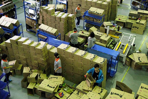 Workers from Tmall.com prepare cartons for goods that need to be sent by post at a sorting center in Guangzhou, Guangdong province. According to iResearch Consulting Group, Tmall led China's B2C market in the first quarter of this year, accounting for 58.6 percent of the 373.7 billion yuan ($61.02 billion) market between January and March. (Photo: China Daily)