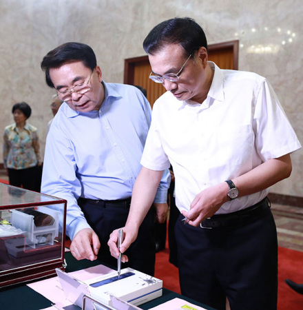 Premier Li Keqiang, accompanied by Bai Chunli, president of the Chinese Academy of Sciences, tries an electronic pen developed by the academy before sitting down for talks with leading scientists on the country's development of science. (Photo/China Daily)