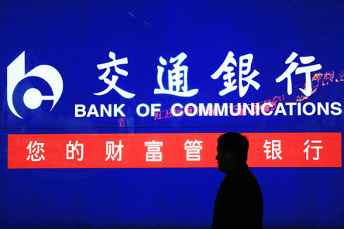 A passer-by in front of a Bank of Communications branch in Nanjing, Jiangsu province, in March. (Photo/China Daily)