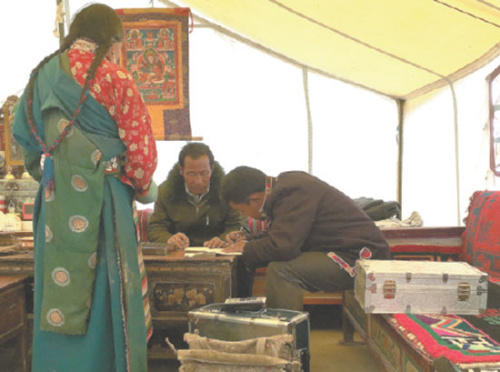 A bank clerk helps a herdsman to fill in a form for a loan in a family tent in Ngari prefecture. (Photo/China Daily)