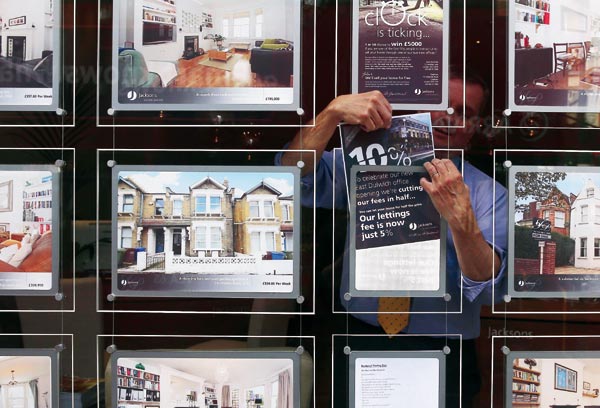A Jacksons Estate Agent employee hangs a promotional sign in Dulwich, London. (Photo / Provided to China Daily)