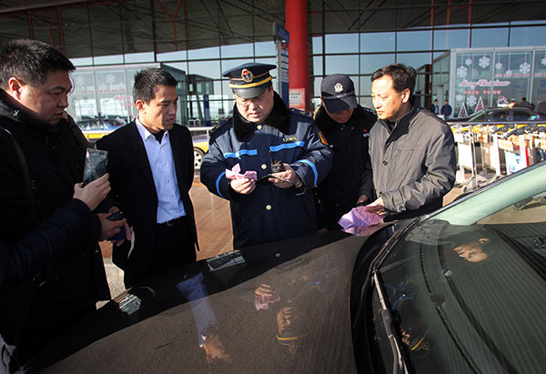 Police examine the licenses of drivers at Beijing Capital International Airport to see if they are registered drivers for commercial services in Beijing. (Zou Hong / China Daily)