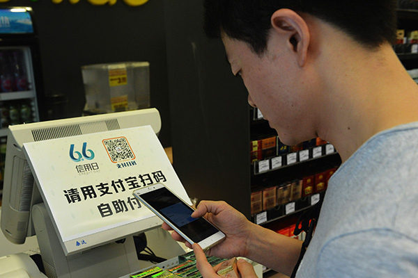 A man uses his smartphone to scan a Alipay two-dimensional code for payments at the first unmanned supermarket in Hangzhou, Zhejiang province. (Asianewsphoto by Long Wei)