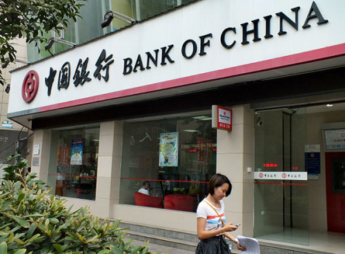 A pedestrian walks past a branch of the Bank of China Ltd in Yichang, Hubei province. As companies face more operating difficulties, rising NPLs and NPL ratios at banks are likely to continue.(Liu Junfeng/China Daily)
