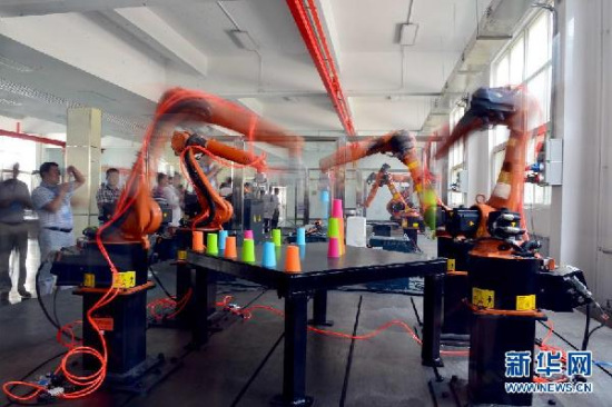 Visitors observe a robot workstation at an intelligent robot research institute in Shandong, June 21, 2015. (Photo/Xinhuanet)
