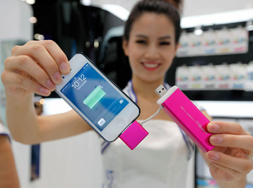 A model demonstrates an iPhone 5 and a mobile charger at an exposition in Beijing. (Photo provided to China Daily)