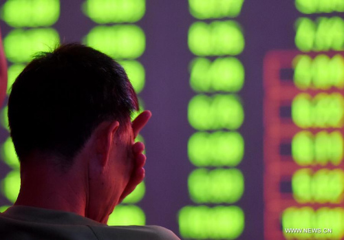 An investor looks through stock information at a trading hall of a securities firm in Luoyang, central China's Henan Province, Aug. 24, 2015.  (Photo: Xinhua/Zhang Yixi)