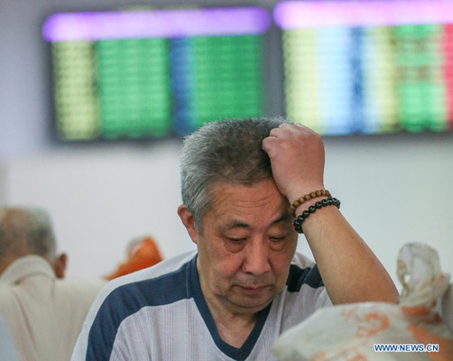 An investor looks through stock information at a trading hall of a securities firm in Shanghai, east China, Aug. 25, 2015.  (Photo: Xinhua/Ding Ting)