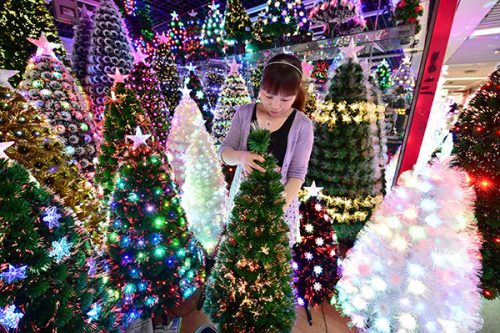 A sales person sorts and arranges decorative Christmas trees for exports in Yiwu, Zhejiang province.(Lyu Bin/China Daily)