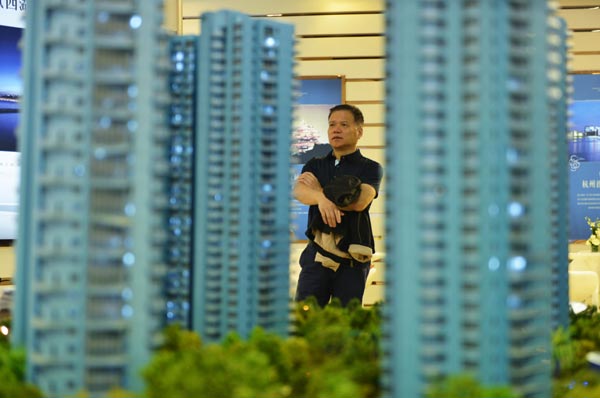 A man examines property models at a housing sales center in Hangzhou, capital of Zhejiang province. (Photo/China Daily)
