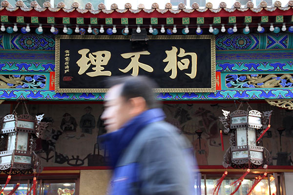 A pedestrian walks past a Goubuli restaurant in Tianjin. The company is planning to issue 30 million shares on the National Equities Exchange and Quotations. (Photo/China Daily)