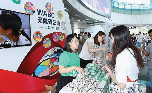 A Tencent employee, and charity supporter, explains to a visitor how to take part in Tencent's program. (Photo provided to China Daily)