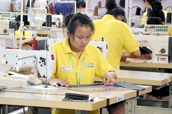 Employees measure cloth before cutting at a private textiles and garments company in Nanjing, Jiangsu province. (Photo/China Daily)