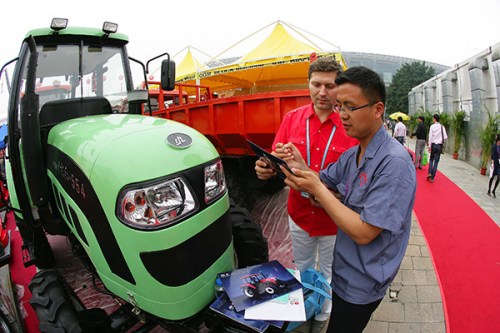 A Kazakhstan businessman tries to get information from a Chinese staff member about a China-made tractor during a trade event early this year in Guangzhou, Guangdong province. (Photo provided to China Daily)