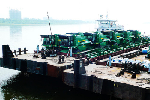 A barge loaded with 10 made-in-China combine harvesters at Heihe port, Heilongjiang province. The vehicles were sold to companies in Blagoveshchensk of Russia. (Photo provided to China Daily)