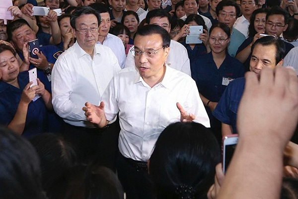 Premier Li Keqiang meets with workers as he visits a mining equipment manufacturer in Luoyang, Henan province, on Sept23 2015. The premier called for workers not just to rely on their expertise but also on technology. (Photo/China News Service)