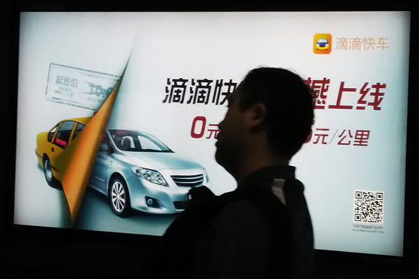 A pedestrian walks past an advertisement of Didi Kuaidi, China's largest car-booking company, in Beijing. (Photo/China Daily)
