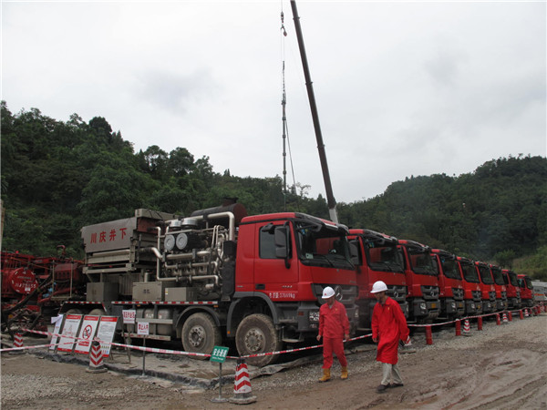 A foreman and a visitor pass fracturing trucks in a shale gas field in Gongxian county, Sichuan province. (Photo by Huang Zhiling/chinadaily.com.cn)