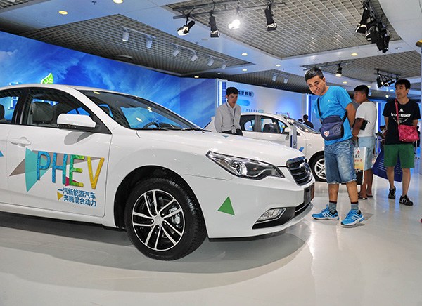 Visitors check a hybrid new-energy car at an auto show in Changchun, Jilin province. A total of 72,711 new-energy vehicles were sold in the country in the first six months of the year. (Photo/Xinhua)