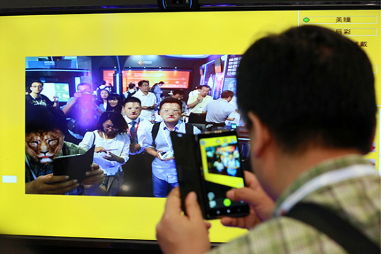 Visitors experience Alibaba Group Holding Ltd's virtual magic face-changing tech at an international information technology expo in Beijing. (Photo/China Daily)