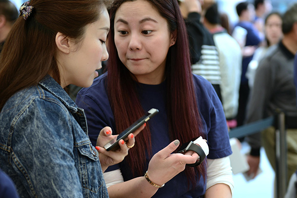 Two women try to make their Apple watches compatible with an iPhone 6 plus at an Apple store in Hangzhou, Zhejiang province. (Photo/China Daily)
