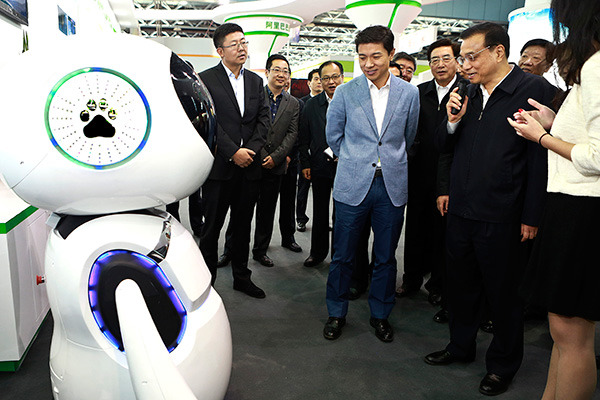 Premier Li Keqiang talks with a domestically developed intelligent robot during a weeklong innovation expo in Beijing starting on Monday. (Photo/China Daily)