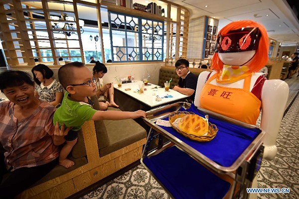 A boy is fascinated by a robotic waitress at a restaurant in Haikou, Hainan province. (Photo/Xinhua)