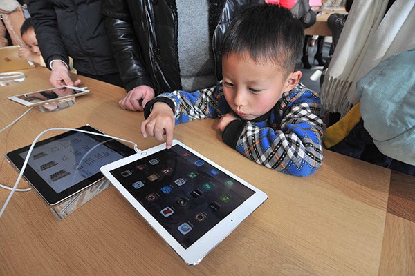 A child touches iPad in an Apple store, Hangzhou, Zhejiang province, Jan 24, 2015. (Photo/China Daily)