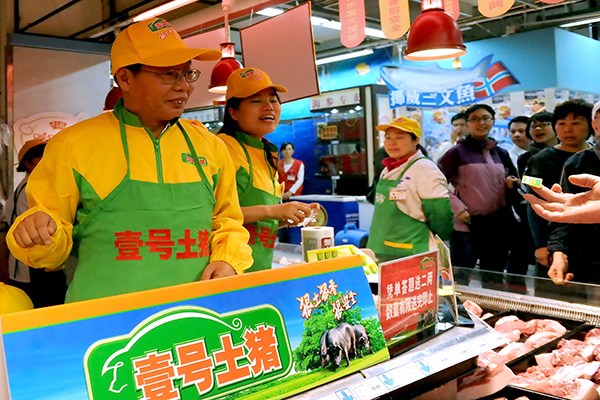 Chen Sheng (left), president of Tiandi No 1, a newly listed company on the New Third Board, promotes his No 1 Original Pig products at a supermarket in Beijing. The company plans to issue an additional 25 million shares for 25 yuan each to raise 625 million yuan. (Photo/China Daily)