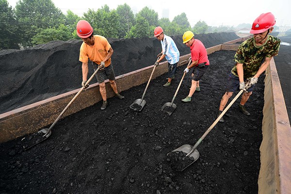 Workers unload coal for power generation at a railway station in Nanchang, Jiangxi province. Among all the listed coal firms, Shaanxi Coal Industry Co Ltd was the worst-hit in the sector after it posted losses of 1.8 billion yuan ($284 million) in the first nine months. (Photo/China Daily)