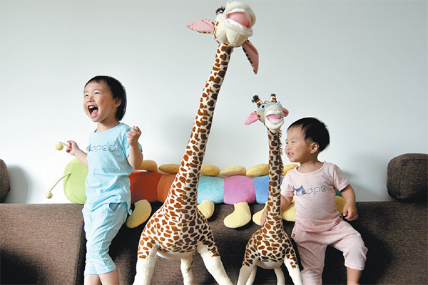 Two sisters, aged 3 and 1, are happy to get their gifts of giraffe toys on Children's Day on June 1, in Hangzhou, capital of Zhejiang province. The photographer has been tracking the children's progress over the years in this two-children family. (Photo provided to China Daily)