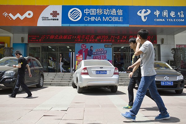 Pedestrians walk past a telecom services outlet in Taiyuan, Shanxi province. Shares of China United Network Communications Ltd surged by 6.96 percent to 7.07 yuan ($1.1) on Nov 5, 2015. (Photo/China Daily)