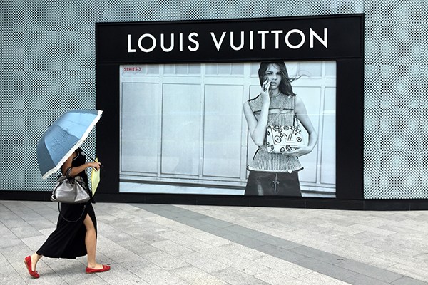 A pedestrian walks past a Louis Vuitton shop in Fuzhou, Fujian province. The French luxury goods company said its business in China was battered in the third quarter due to the wild stock market swings. (Photo/China Daily)