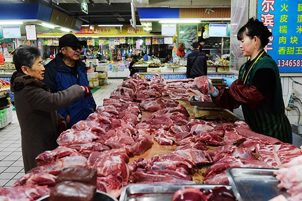 Two senior people buy pork at a farmer's market in Qingdao, Shandong province. According to media reports, people in Asia consumed 6 billion tons of processed meat in 2014. (Photo/China Daily)