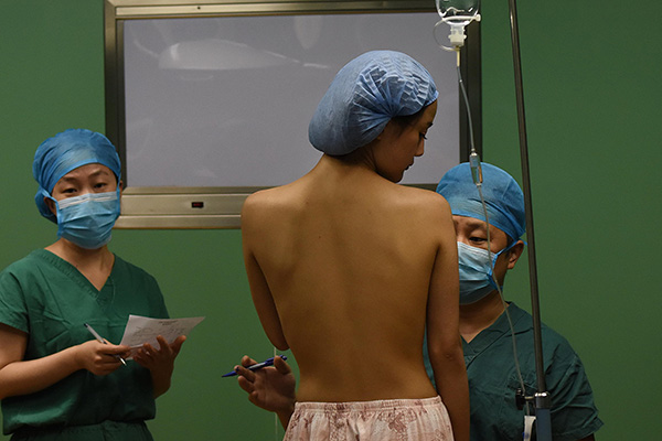 A doctor prepares a patient for breast-enhancement surgery at a hospital in Hefei, Anhui province, in July. (Photo/China Daily)