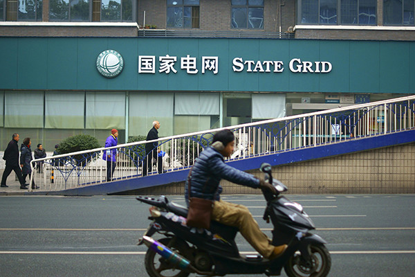 A man rides past a branch of State Grid Corp in Yichang, Hubei province. (Photo/China Daily)