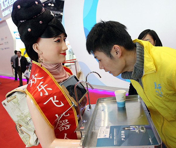 A man looks at a robot which can deliver food at the World Robot Conference 2015 in Beijing, Nov 23, 2015. (Photo/China Daily)
