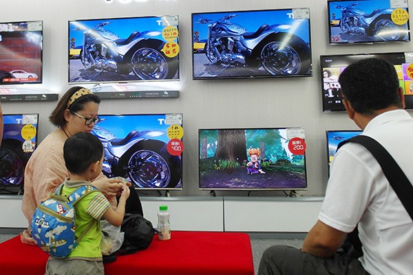 A woman and her kid select smart TV sets at a TCL television outlet in Yichang, Hubei province. (Photo/China Daily)