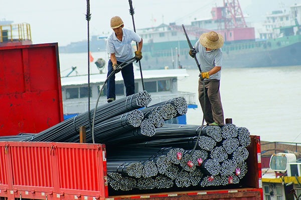 Workers load steel products at a logistics park in Yichang, Hubei province. (Photo/China Daily)