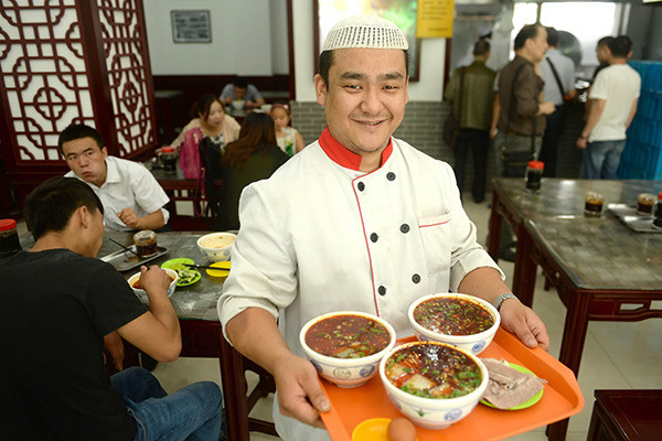 A waiter serves noodles for customers at a noodle restaurant in Lanzhou, Gansu province. (Photo/Xinhua)