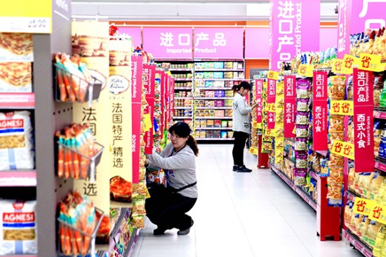 Two employees arrange goods on the shelves at the imported products area of the newly opened Carrefour outlet in Beijing on Friday. The hypermarket is home to more than 40,000 products, of which about 6,000 are imported. [Photo provided to China Daily]