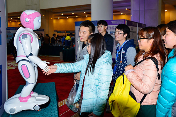 A visitor shakes hands with a robot developed by a Nanjing company at a robotics show in Jinan. (JU CHUANJIANG/CHINA DAILY)
