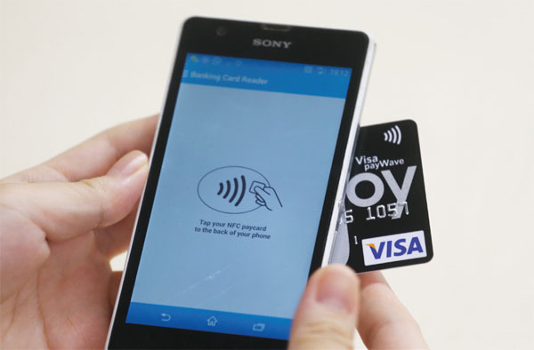 A mobile phone reads the information of a credit card via mobile app Banking Card Reader. Phones with near field communication (NFC) technology can instantly extract credit card information such as the card number, expiry date and transaction records. (Roy Liu/China Daily)